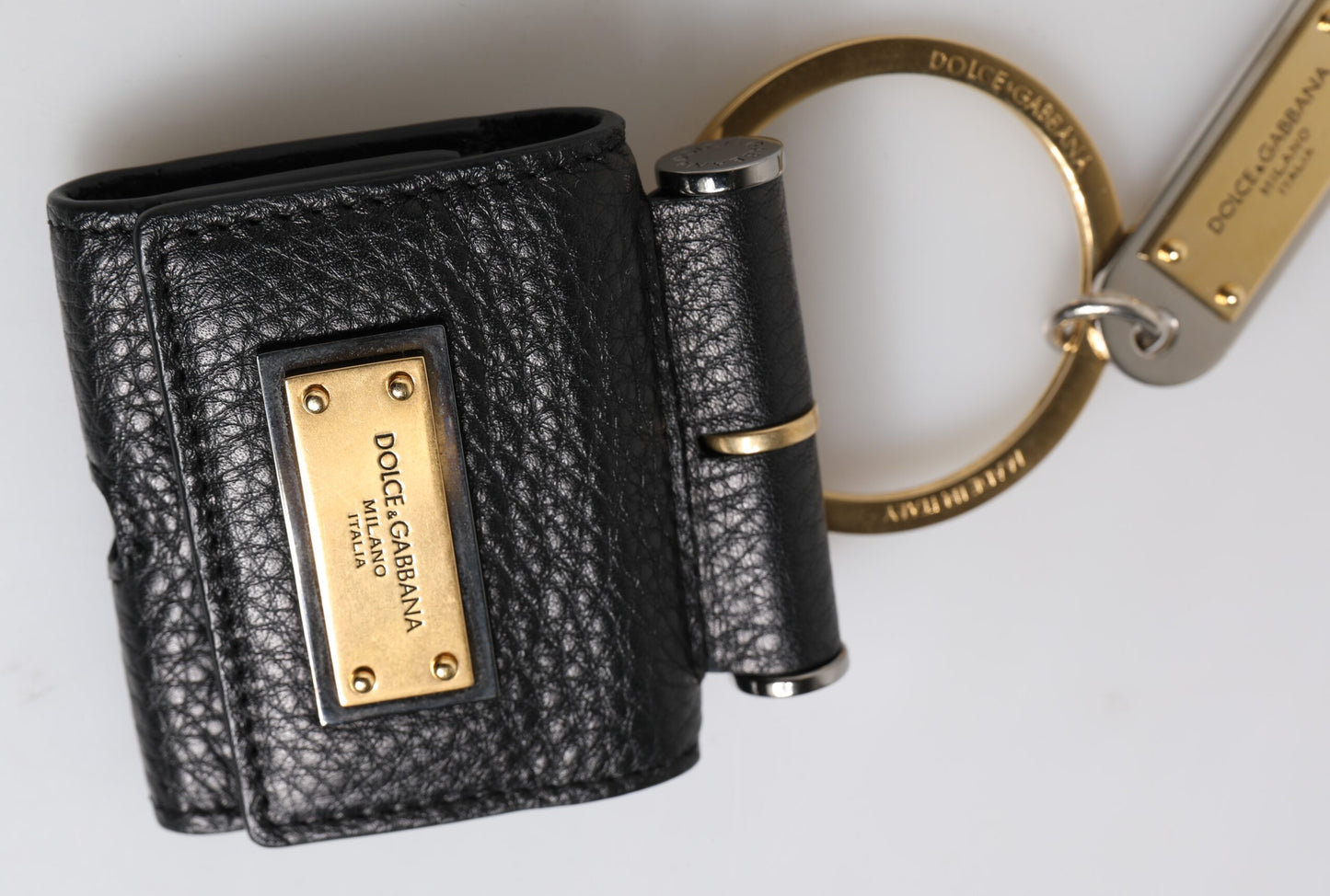 حافظة سماعات Airpods من دولتشي آند غابانا، بحزام جلدي أسود، ولوحة معدنية ذهبية بشعار دولتشي آند غابانا